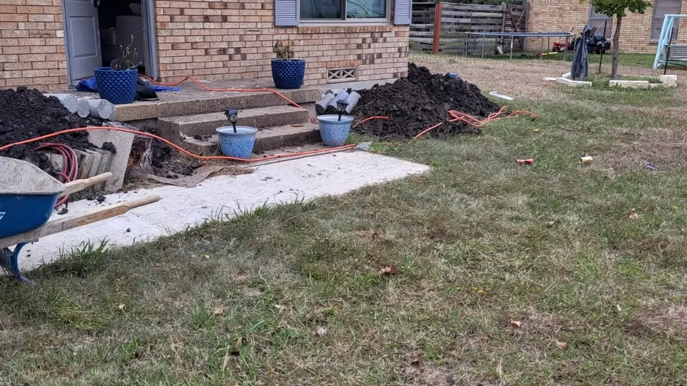 A crew member working in an excavation beside a house